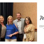 Group of five smiling people holding award