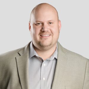 Here's an alt tag for the image: Headshot of a smiling man in a suit.